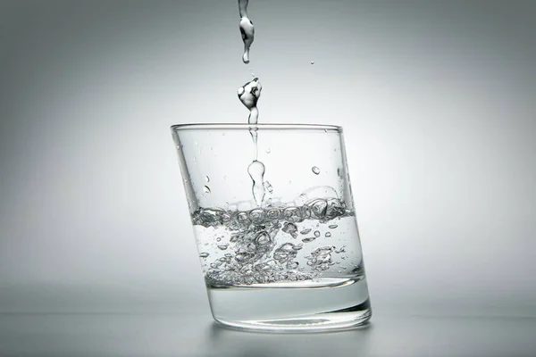 Wasser Ergießt Sich Ein Glas Auf Grauem Hintergrund Nahaufnahme Stockfoto