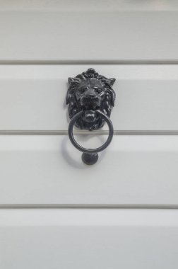 Beyaz ahşap kapıya aslan kafası şeklinde yeni siyah tokmak.