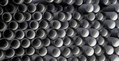 Açık hava deposunda siyah plastik su boruları var.