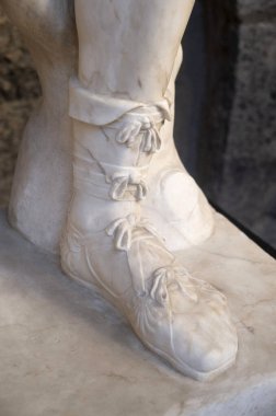 Ancient roman sandals on male legs of marble sculpture in Italy, Europ clipart