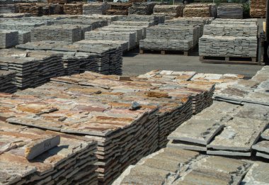 Warehouse with many pallets of gneiss stone slabs closeu clipart