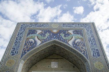 Impressive entrance of Nadir Devanbegi Madrasah with fantastic birds and animals on arch and decoration of ceramic mosaics, calligraphy, and geometric ornaments in Bukhara , Uzbekistan, Asi clipart