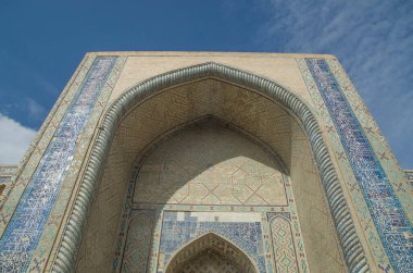 Impressive entrance of Ulugbek Madrasah on arch and decoration of ceramic mosaics, calligraphy, and geometric ornaments in Bukhara , Uzbekistan, Asi clipart