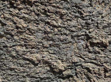 Gri kahverengi volkanik kayalar güneşli bölgede yakındır.