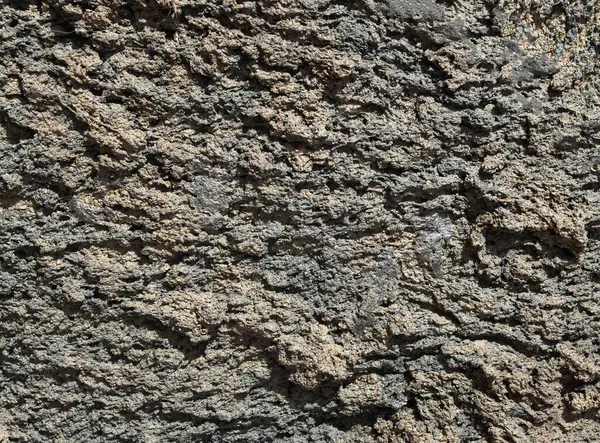 Gri kahverengi volkanik kayalar güneşli bölgede yakındır.