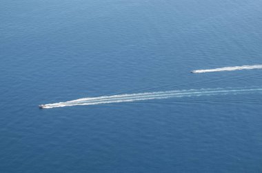 İki hızlı hareket eden tekne ve mavi renkli beyaz köpük izleri.