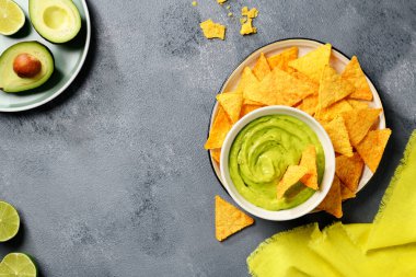 Avokado soslu guacamole ve beyaz kasede mısır cipsi..