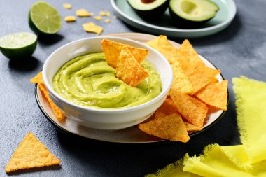 Avokado soslu guacamole ile tortilla mısır cipsi ve beyaz kase. .