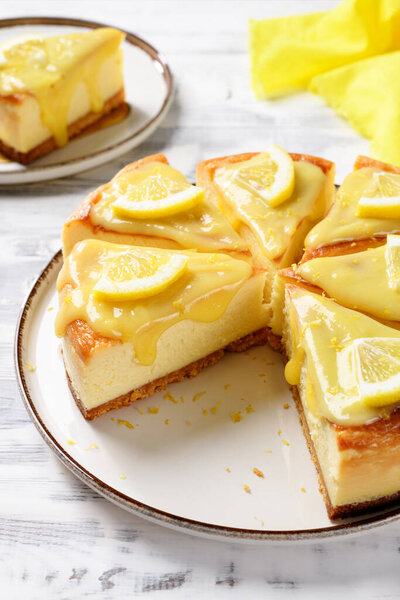 Sliced Fresh baked homemade lemon cheesecake with lemon curd and lemon slices.