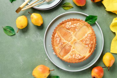 Klasik Pear Frangipane Turtası (Tarte Bourdaloue). Lezzetli sonbahar ve kışın lezzet ve dokuma dolu hamur işi. Üst görünüm, yeşil arkaplan