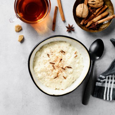 Tarçınlı pudingle süslenmiş taze pirinç pudingi. Her gün için sağlıklı bir kahvaltı. Açık gri arkaplan, üst görünüm