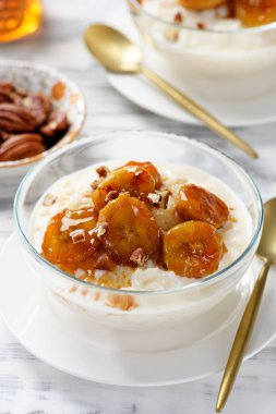 Karamelli muz, bal ve fındıklı taze pirinç pudingi. beyaz tahta arkaplan