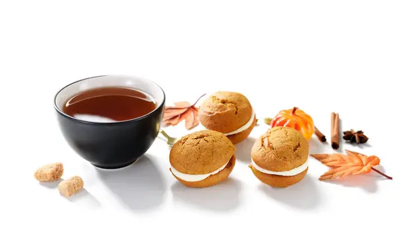 Pumpkin  sandwich cookies with cream cheese filling and cup of tea isolated on white background