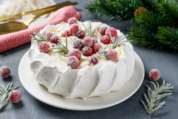 Pavlova meringue cake decorated with frozen cranberry and rosemary. Cake for christmas event.