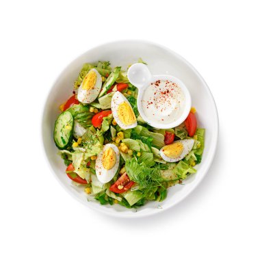 Haşlanmış yumurta, salatalık ve mısırlı sağlıklı yeşil yaz salatası. Beyaz arka planda izole edilmiş. en üstteki görünüm