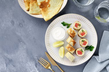 Tuzlu somon, krem peynir ve taze salatalıkla doldurulmuş ev yapımı krep ruloları. Lezzetli aperatif. en üstteki görünüm