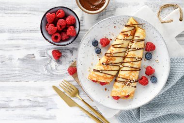 Krep ya da süzme peynirli ince krep, taze böğürtlen ve çikolata soslu fındık serpiştirilmiş. en üstteki görünüm