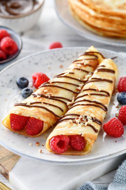 Krep ya da süzme peynirli ince krep, taze böğürtlen ve çikolata sosu serpiştirilmiş fındık.