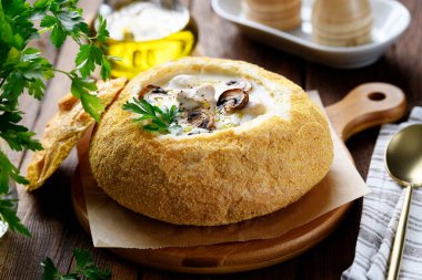 Tavuk ve mantarlı krema çorbası. Çöreğin içinde çok güzel servis ediliyor. Ahşap arkaplan.