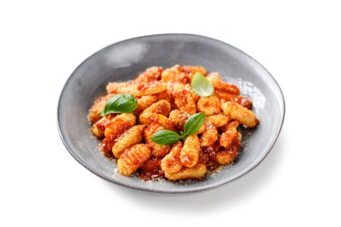 Domates soslu geleneksel İtalyan patates gnocchi, parmesan peyniri ve beyaz arka planda izole edilmiş taze fesleğen yaprakları.
