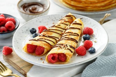 İnce krep veya süzme peynirli krep, taze böğürtlen ve çikolata sosu serpiştirilmiş fındık.