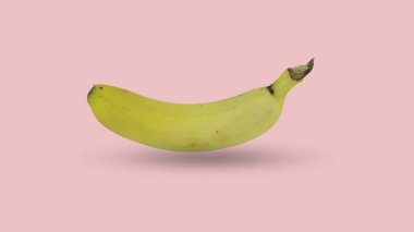 Yumuşak pembe bir zemin üzerinde izole edilmiş bir grup olgun sarı muz canlı renklerini ve doğal dokusunu sergiliyor. Yemek ve sağlıkla ilgili kavramlar için ideal..