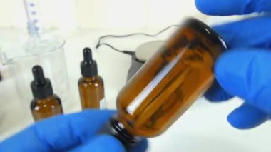 Profesyonel bir kozmetik laboratuvarında cam bir deney şişesinde şeffaf, şeffaf bir serumu sallama sürecini gösteren bir video. Klip, kozmetik formülasyonunda yer alan hassasiyet ve uzmanlığı ve cilt ürünleri oluşturulmasını vurguluyor. 
