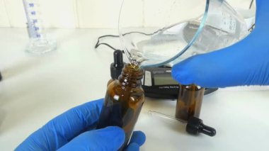Profesyonel bir kozmetik laboratuvarında cam bir deney şişesinde şeffaf, şeffaf bir serumu sallama sürecini gösteren bir video. Klip, kozmetik formülasyonunda yer alan hassasiyet ve uzmanlığı ve cilt ürünleri oluşturulmasını vurguluyor. 
