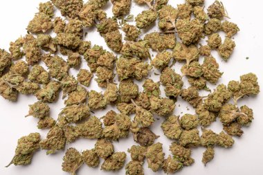 Kuru marihuana tomurcukları, kurutulmuş kenevir çiçekleri, tıbbi marihuana, beyaz masanın üzerinde yatan.