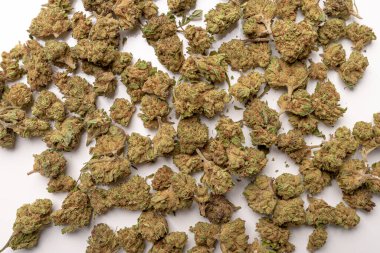 Kuru marihuana tomurcukları, kurutulmuş kenevir çiçekleri, tıbbi marihuana, beyaz masanın üzerinde yatan.