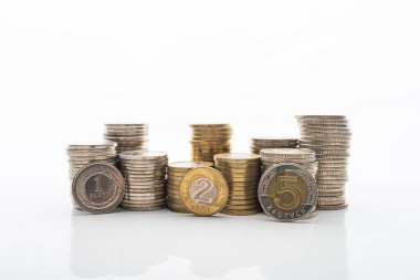 Pürüzsüz yansıtmalı beyaz arka planda duran madeni paraların fotoğrafı. Ev bütçesi, tasarruf, zenginlik kavramı. 1, 2 ve 5 PLN paraları yığının önünde duruyor.