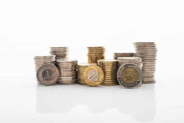 Pürüzsüz yansıtmalı beyaz arka planda duran madeni paraların fotoğrafı. Ev bütçesi, tasarruf, zenginlik kavramı. 1, 2 ve 5 PLN paraları yığının önünde duruyor.