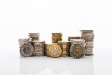 Pürüzsüz yansıtmalı beyaz arka planda duran madeni paraların fotoğrafı. Ev bütçesi, tasarruf, zenginlik kavramı. 1, 2 ve 5 PLN paraları yığının önünde duruyor.