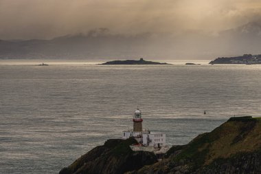 Photo of Howth Cliffs, Dublin, Ireland. Cloudy landscape with Ireland coastline, Howth Lighthouse and North Sea. Howth Cliffs Walk. clipart
