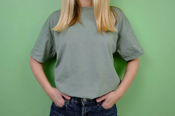 女模特穿着绿色T恤和牛仔裤站在绿墙边 手的姿势和情感演播室拍摄一个女孩 情感与美的概念 — 图库照片