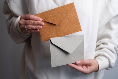 Kadın el kâğıdı zarf ve kutu tutuyor. Yeni posta, mesaj. Posta servisi. Genç kız mektup ya da paket istiyor. Boş zarf, boş alan. İnsanlarla iletişim. Zarf kapatma