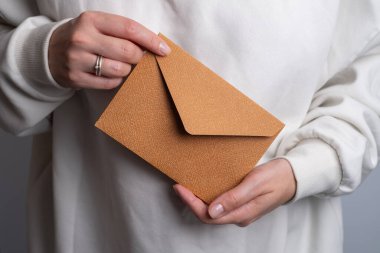 Kadın el kâğıdı zarf ve kutu tutuyor. Yeni posta, mesaj. Posta servisi. Genç kız mektup ya da paket istiyor. Boş zarf, boş alan. İnsanlarla iletişim. Zarf kapatma