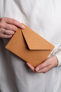 Kadın el kâğıdı zarf ve kutu tutuyor. Yeni posta, mesaj. Posta servisi. Genç kız mektup ya da paket istiyor. Boş zarf, boş alan. İnsanlarla iletişim. Zarf kapatma