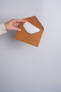 Kadın el kâğıdı zarf ve kutu tutuyor. Yeni posta, mesaj. Posta servisi. Genç kız mektup ya da paket istiyor. Boş zarf, boş alan. İnsanlarla iletişim. Zarf kapatma