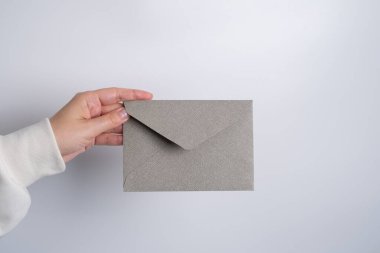 Kadın el kâğıdı zarf ve kutu tutuyor. Yeni posta, mesaj. Posta servisi. Genç kız mektup ya da paket istiyor. Boş zarf, boş alan. İnsanlarla iletişim. Zarf kapatma