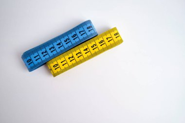 Açık arkaplanda çok renkli mezuralar. Uzunluk ve hacim ölçme aracı. Dikiş üretiminde veya insan vücudunun hacminde ölçüm yapmak için bant