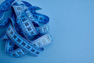 Mavi arka planda mavi bir mezura. Uzunluk ve hacim ölçme aracı. Giysi endüstrisinde veya insan vücudunun hacmini ölçmek için bant