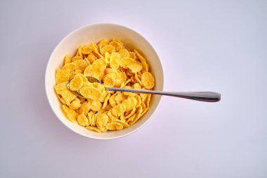 Beyaz arka planda kırmızı bir kasede mısır gevreği. Lezzetli tatlı kahvaltı. Beslenme ve sağlık konsepti