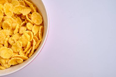 Beyaz arka planda kırmızı bir kasede mısır gevreği. Lezzetli tatlı kahvaltı. Beslenme ve sağlık konsepti