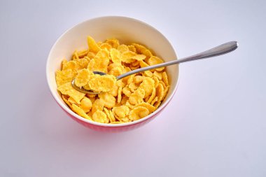 Beyaz arka planda kırmızı bir kasede mısır gevreği. Lezzetli tatlı kahvaltı. Beslenme ve sağlık konsepti