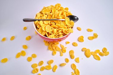 Beyaz arka planda kırmızı bir kasede mısır gevreği. Lezzetli tatlı kahvaltı. Beslenme ve sağlık konsepti