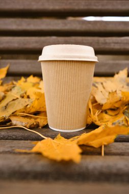 Sonbahar yapraklarının dokusunda kağıt kapaklı kağıt bardak. Ekoloji ve doğa. Tek kullanımlık kağıt bardakları kapatın. Eko materyali. Sıcak içecekler için bir bardak. Metin için boş alan, maket yap