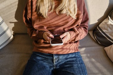 Woman is holding a modern smartphone, sending a text message or using an app on her mobile phone. Internet technology user. Smartphone close-up. Focus on the phone screen
