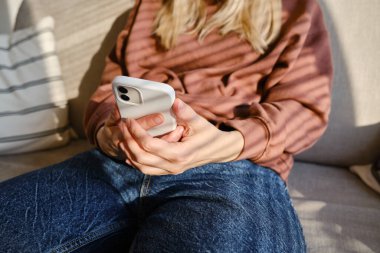 Woman is holding a modern smartphone, sending a text message or using an app on her mobile phone. Internet technology user. Smartphone close-up. Focus on the phone screen