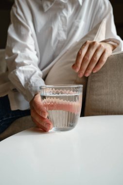 Yatakta uyuyan bir kızın yanında bir bardak su. İyi sabahlar. Pijamalı bir kadın. Sağlıklı yaşam tarzı, sağlık. Düzgün beslenme. İçme suyu. Suyla sabah. Çarşaflarda güneş ışığı. Yastık, battaniye